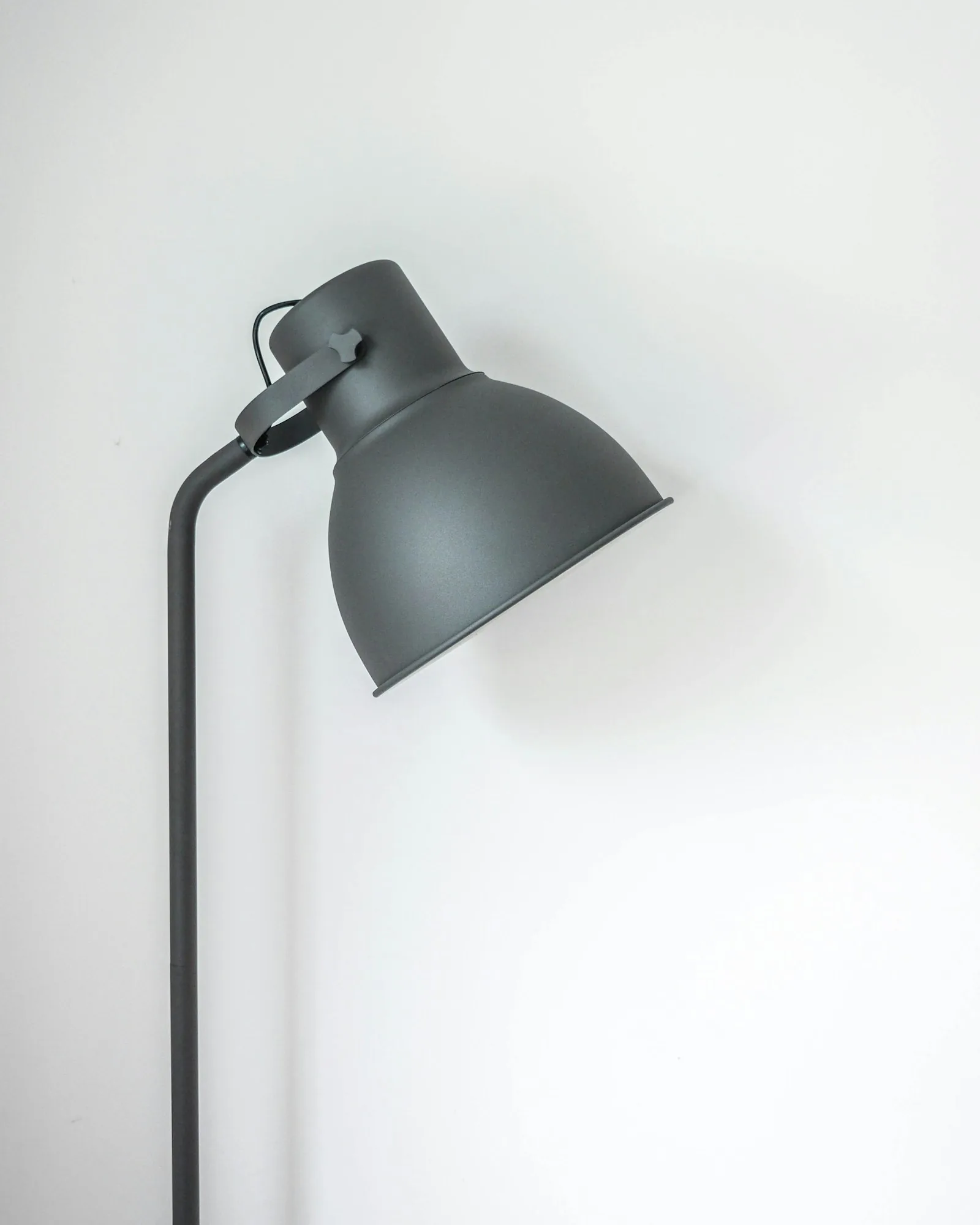 Arc Task Lamp in graphite casting warm light against a pale wall